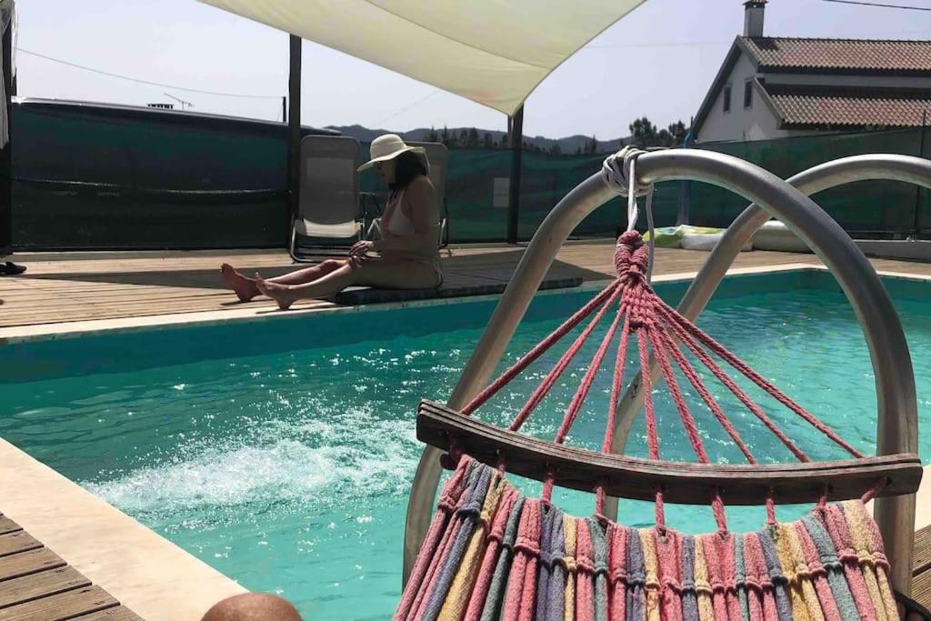 een vrouw zit naast een zwembad bij Aires Orchard Holiday Apartment 
