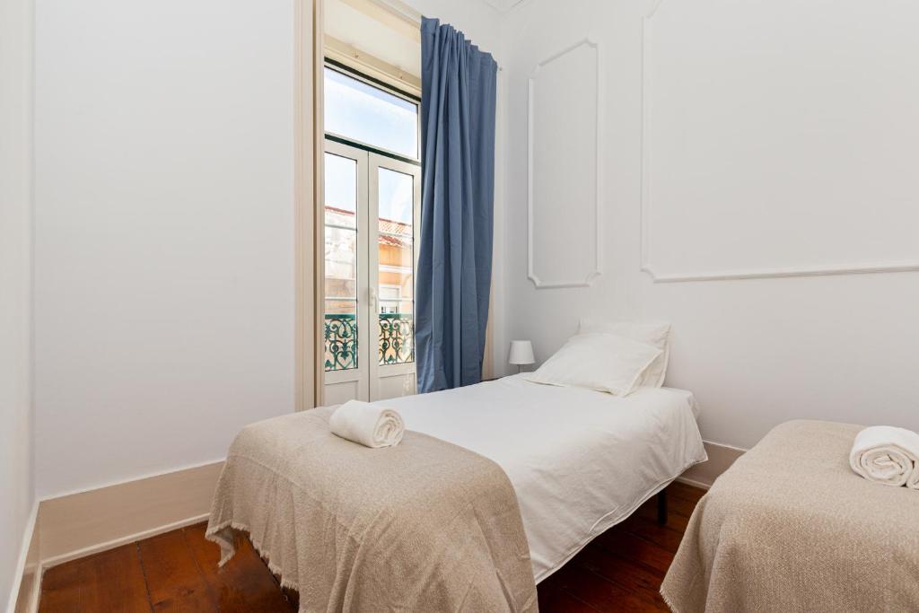 una camera bianca con due letti e una finestra di 4BR Lisbon Apartment - Central Location a Lisbona