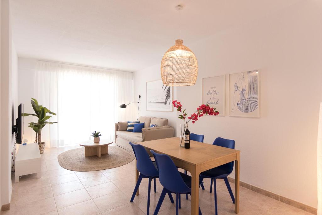 a dining room with a table and blue chairs at Beach Paradise Flat in Denia Centre w/ Large Pool in Denia