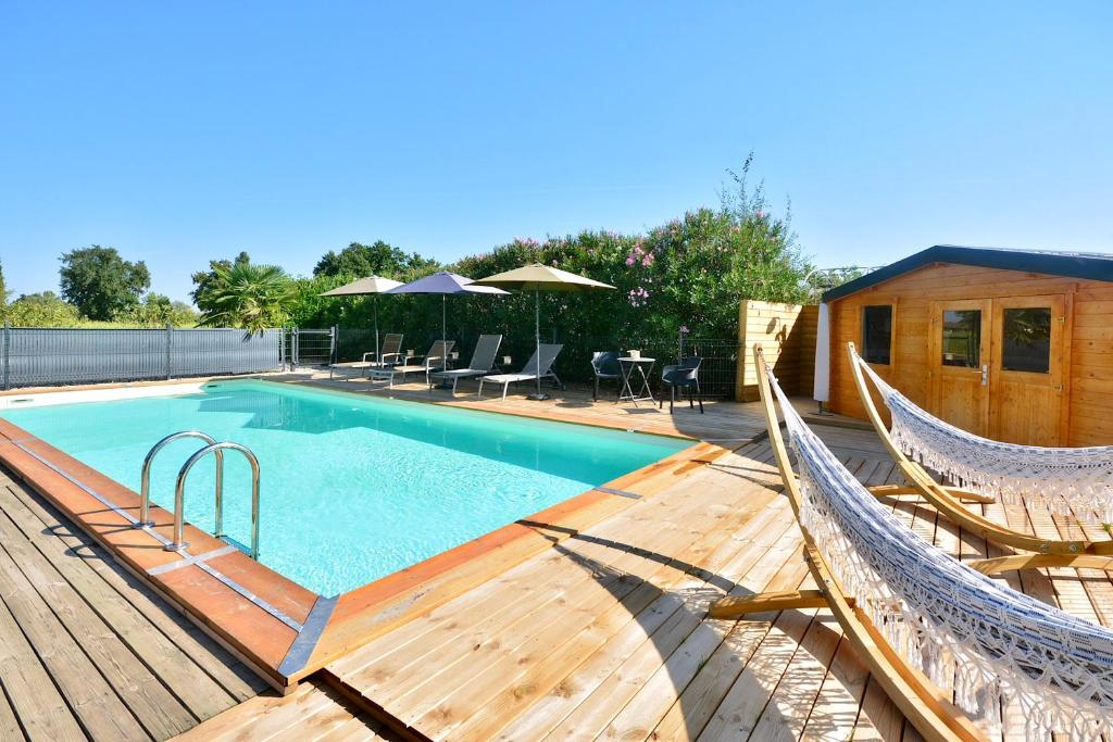 een zwembad met twee hangmatten op een houten terras bij Gîte le Mizériat - Appartement avec piscine privée in Saint-Didier-sur-Chalaronne