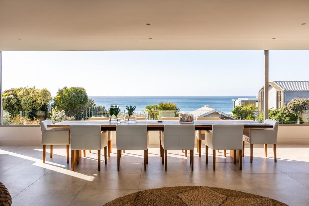 una sala da pranzo con tavolo e sedie e l'oceano di 41 on Beachy Head - Luxury Villa 100m from the beach a Plettenberg Bay