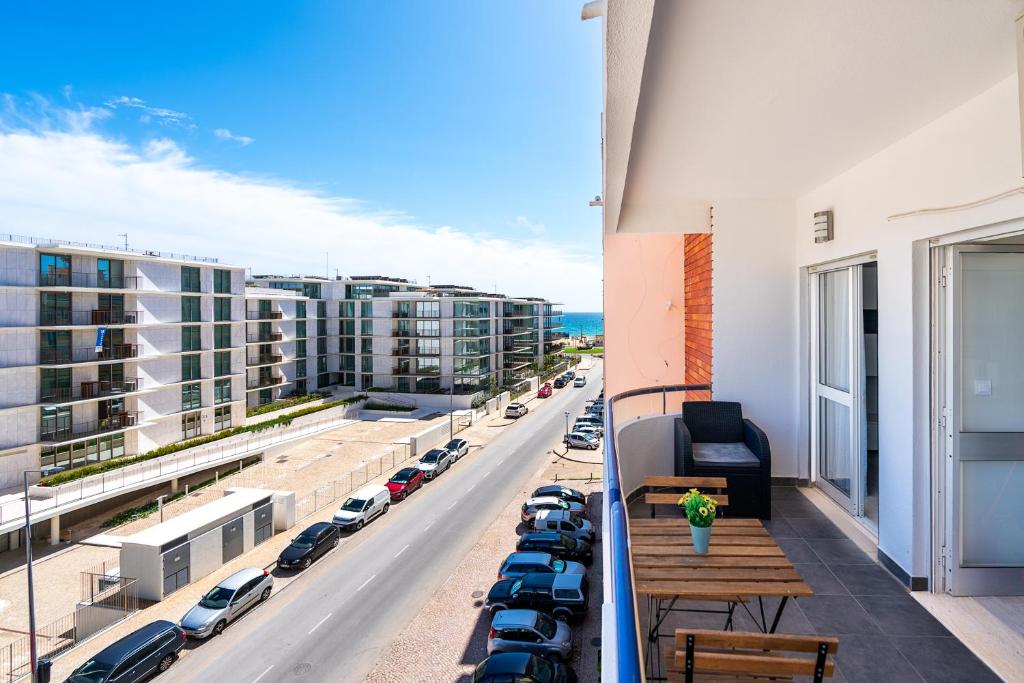 a balcony with a view of a street with parked cars at Beachfront apartment in Armação in Armação de Pêra