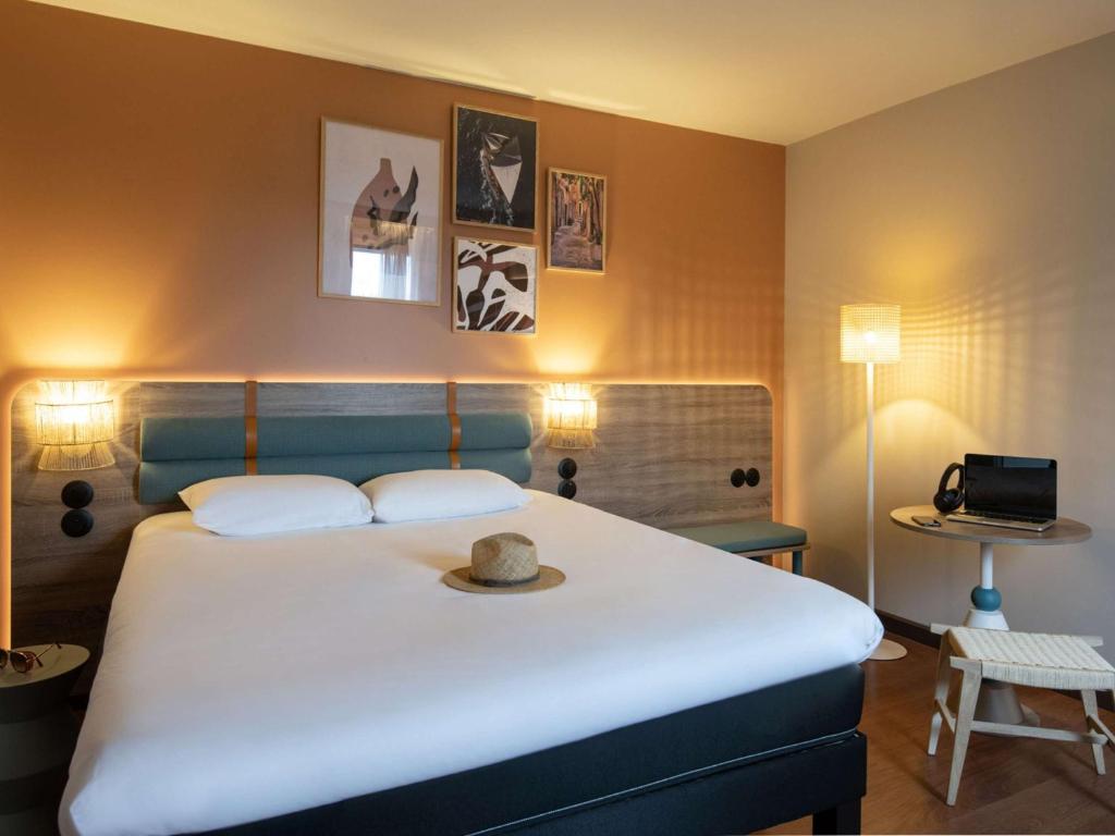 a bedroom with a large bed with a hat on it at ibis Golfe de Saint-Tropez in Cogolin