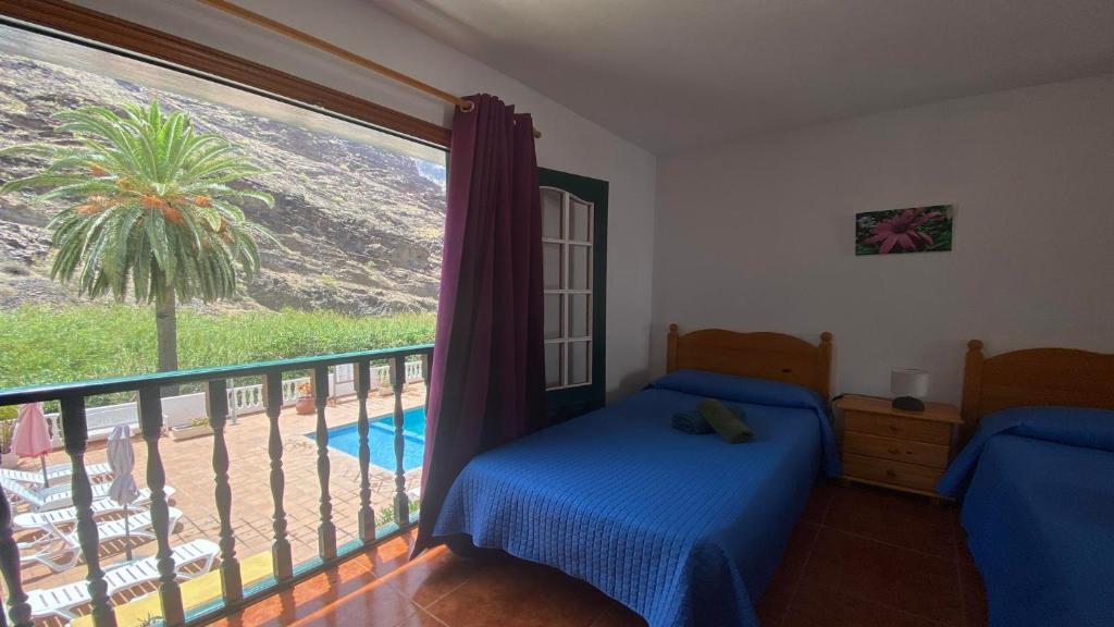 a bedroom with two beds and a balcony with a palm tree at Apartamento Nelly S4 in Valle Gran Rey