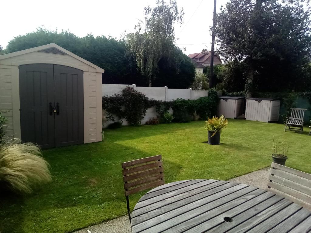 a garden with a shed and a table and a bench at résidence la clairière aux portes de la baie de Somme in Abbeville