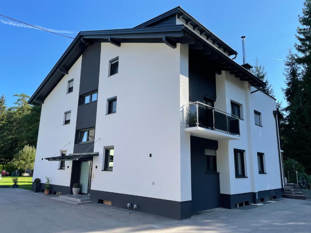 a white and black building with a balcony at FEWO CELINE in Wasserhofen