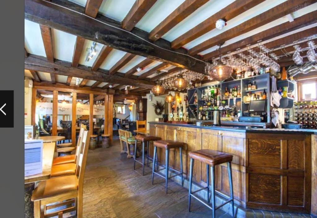 um bar com pisos de madeira e bancos de bar em The Rising Sun Inn em West Bagborough