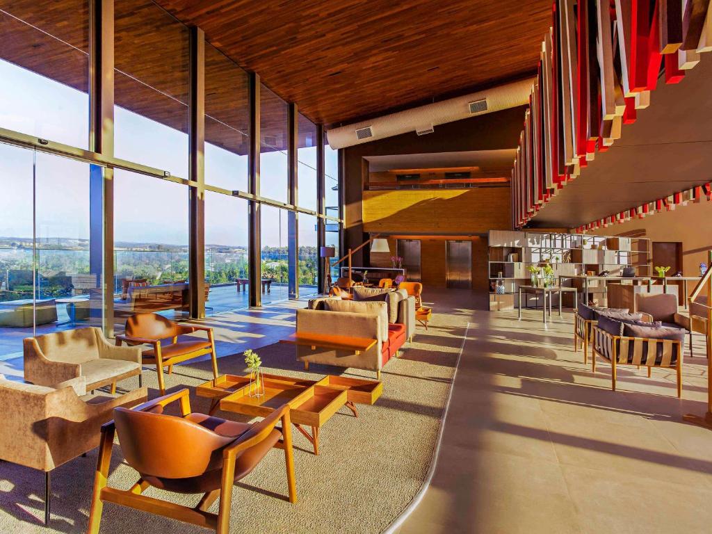 um átrio com cadeiras, mesas e janelas em Novotel Itu Terras de São José Golf & Resort em Itu