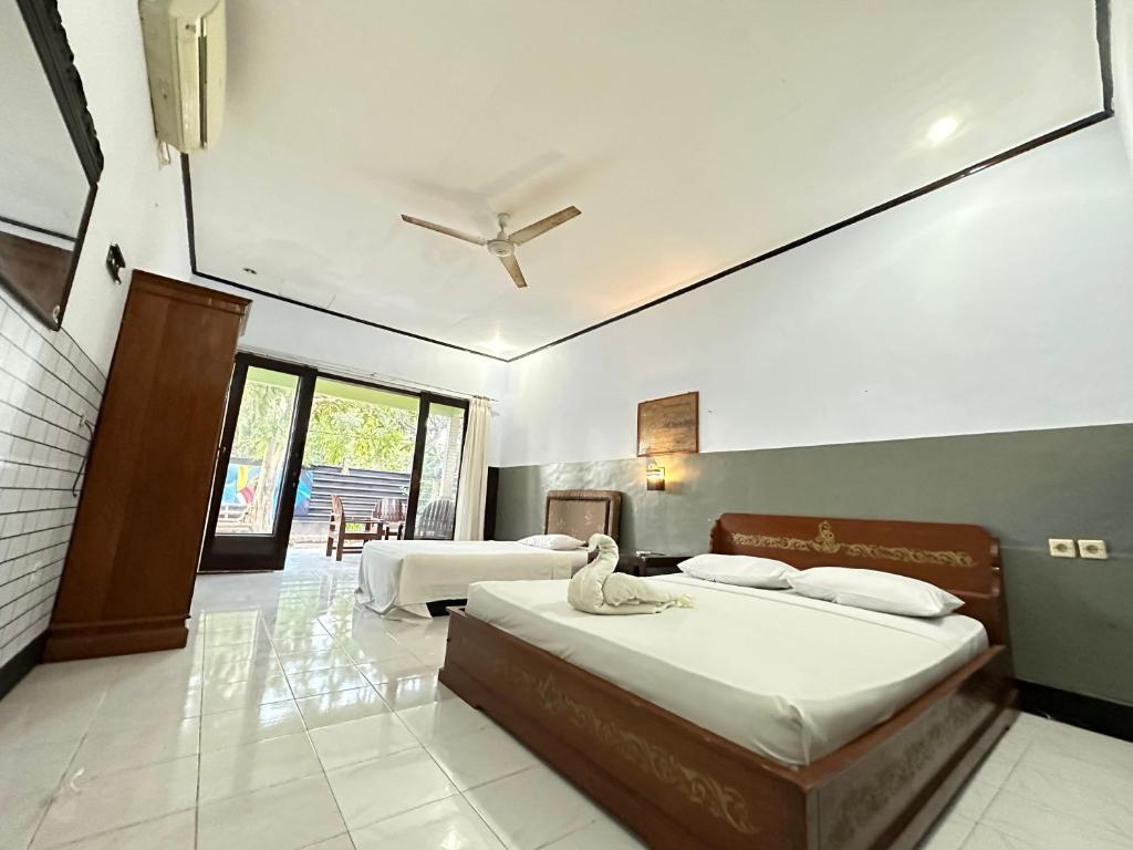 a bedroom with two beds and a ceiling fan at Creative Bungalow Beach Front in Gili Trawangan