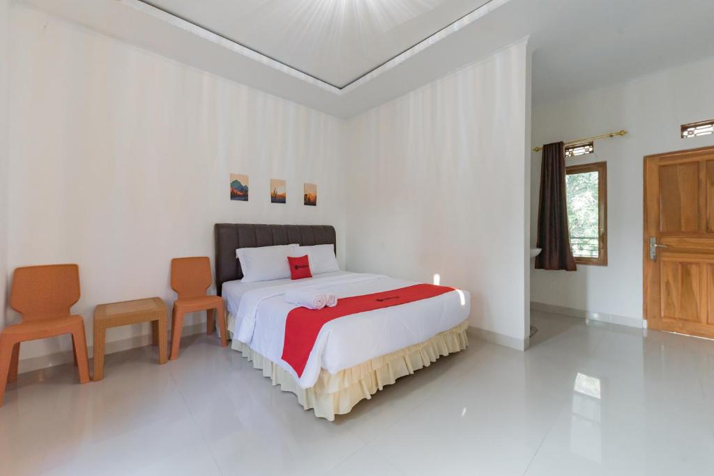 a bedroom with a bed and two chairs in it at RedDoorz near Ciletuh Sukabumi in Cilowa