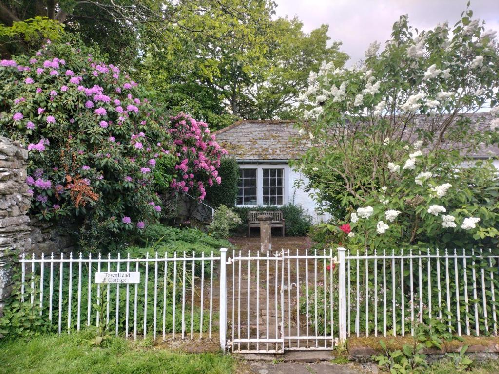 uma cerca branca em frente a uma casa com flores em Townhead Cottage em Patterdale
