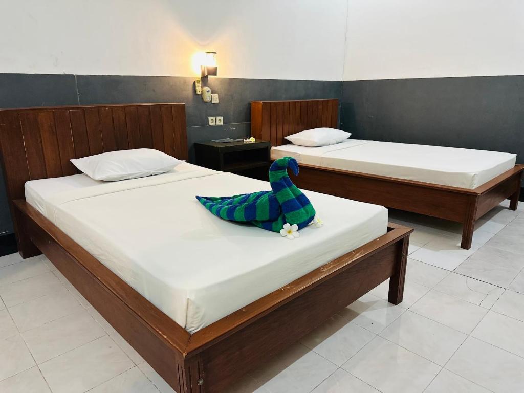 two beds with a toy bird sitting on top of them at Creative Bungalow in Gili Trawangan