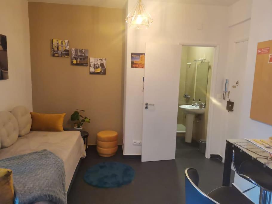 een kamer met een bank en een badkamer met een wastafel bij Enjoy Lisboa! - Near Metro in Amadora
