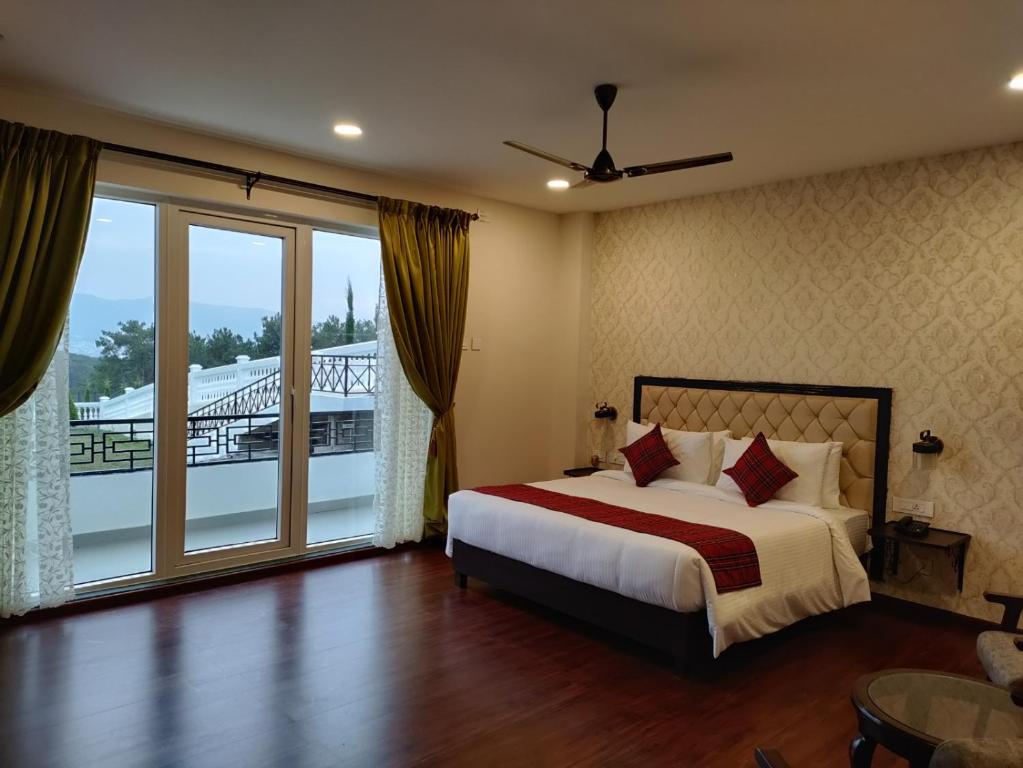 a bedroom with a bed and a balcony at Windermere Hotel in Shillong