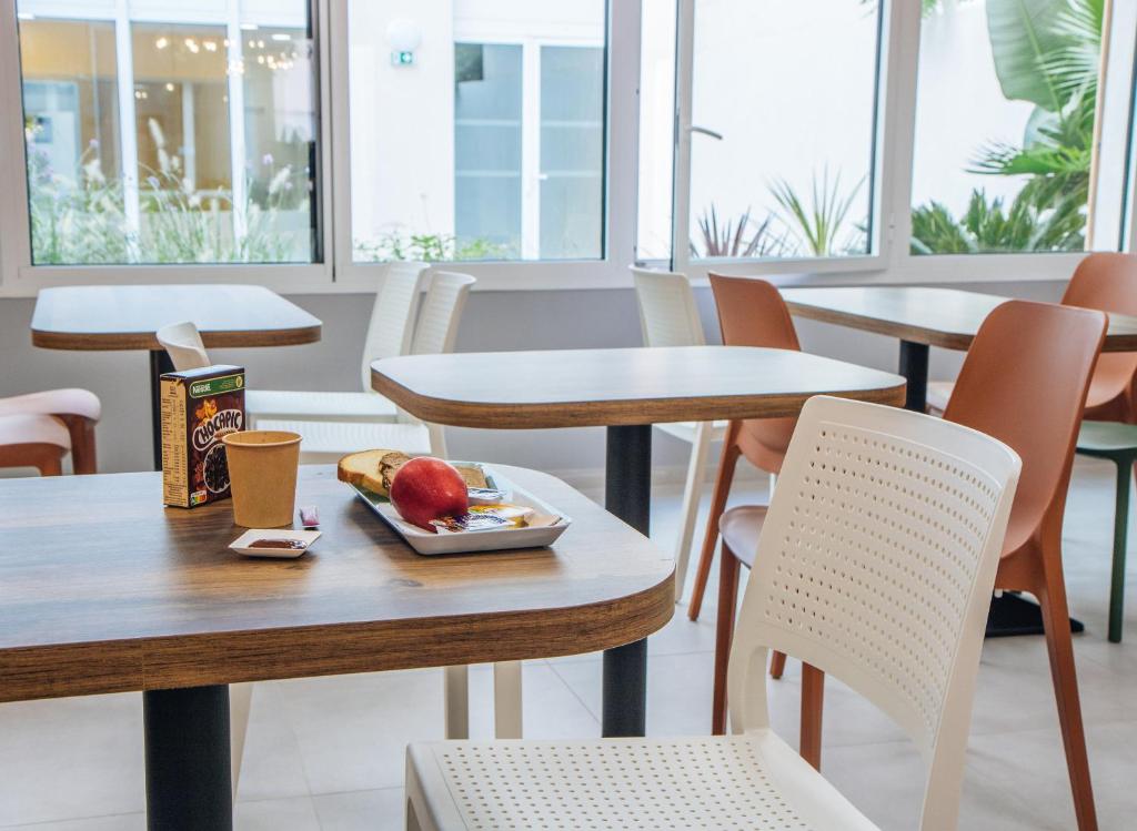 a table and chairs with a plate of food on it at Twenty Business Flats Béziers in Béziers