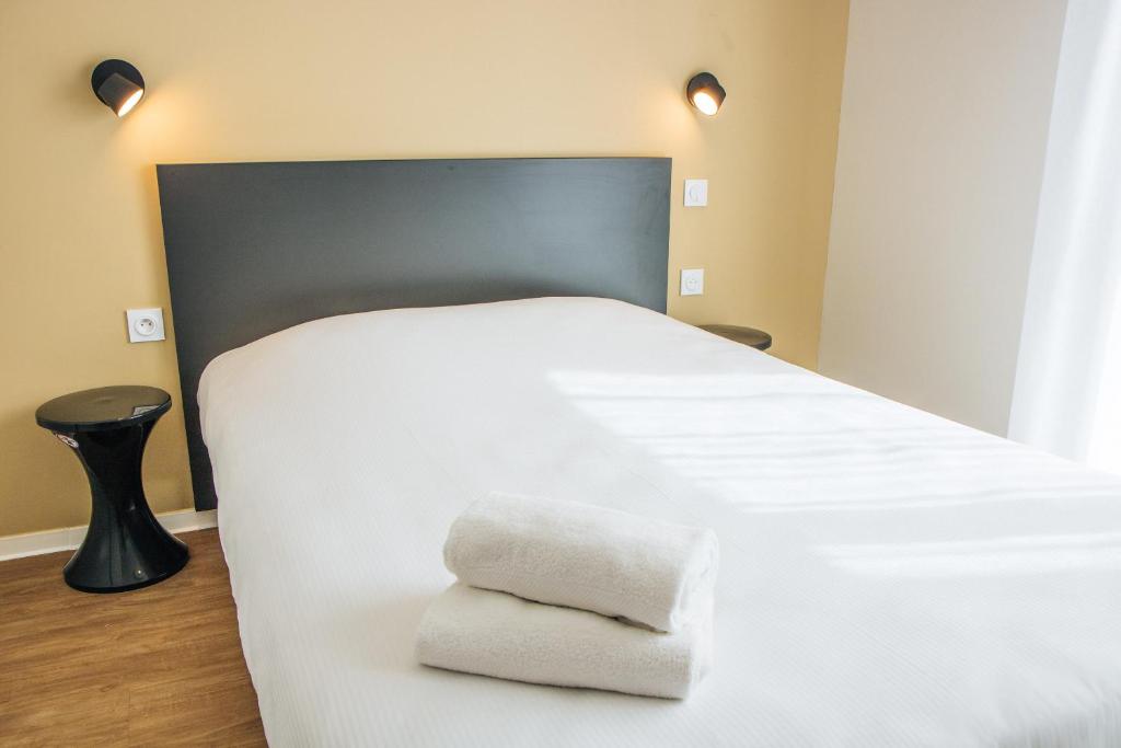 a large white bed with two towels on it at Twenty Business Flats Béziers in Béziers
