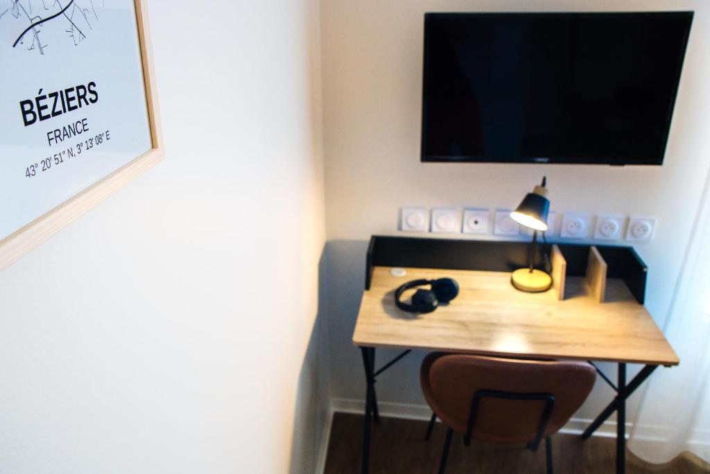 a room with a desk with a lamp and a television at Twenty Business Flats Béziers in Béziers