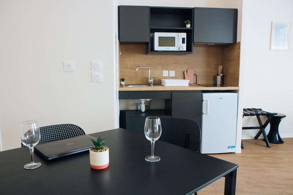 a table with two wine glasses and a laptop on it at Twenty Business Flats Béziers in Béziers