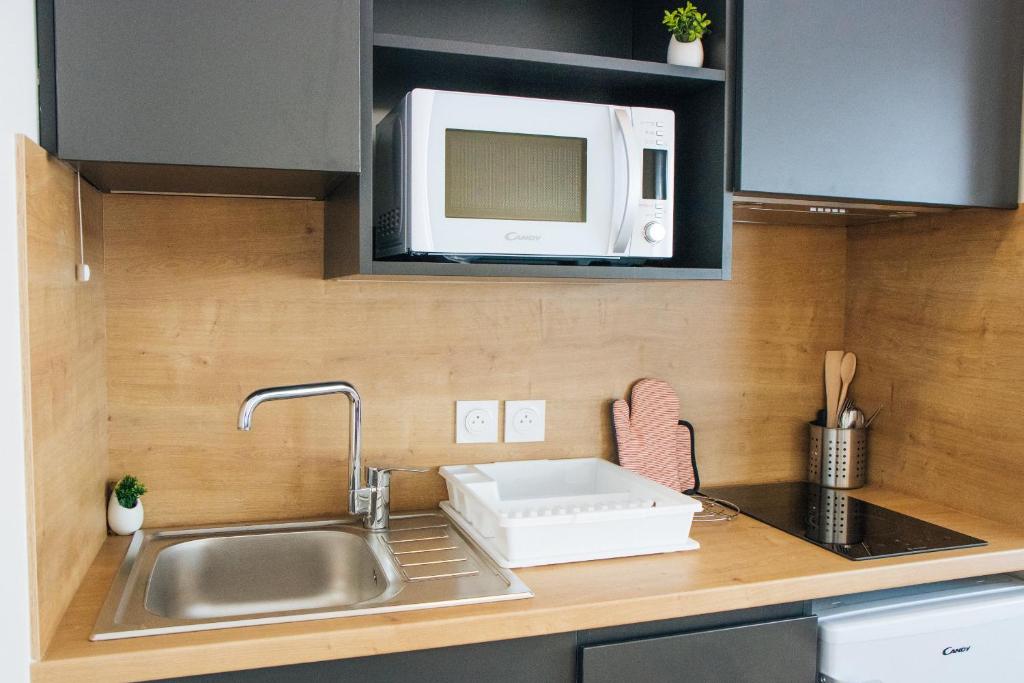 a kitchen with a sink and a microwave at Twenty Business Flats Béziers in Béziers