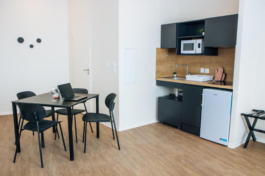 a kitchen with a table and chairs in a room at Twenty Business Flats Béziers in Béziers