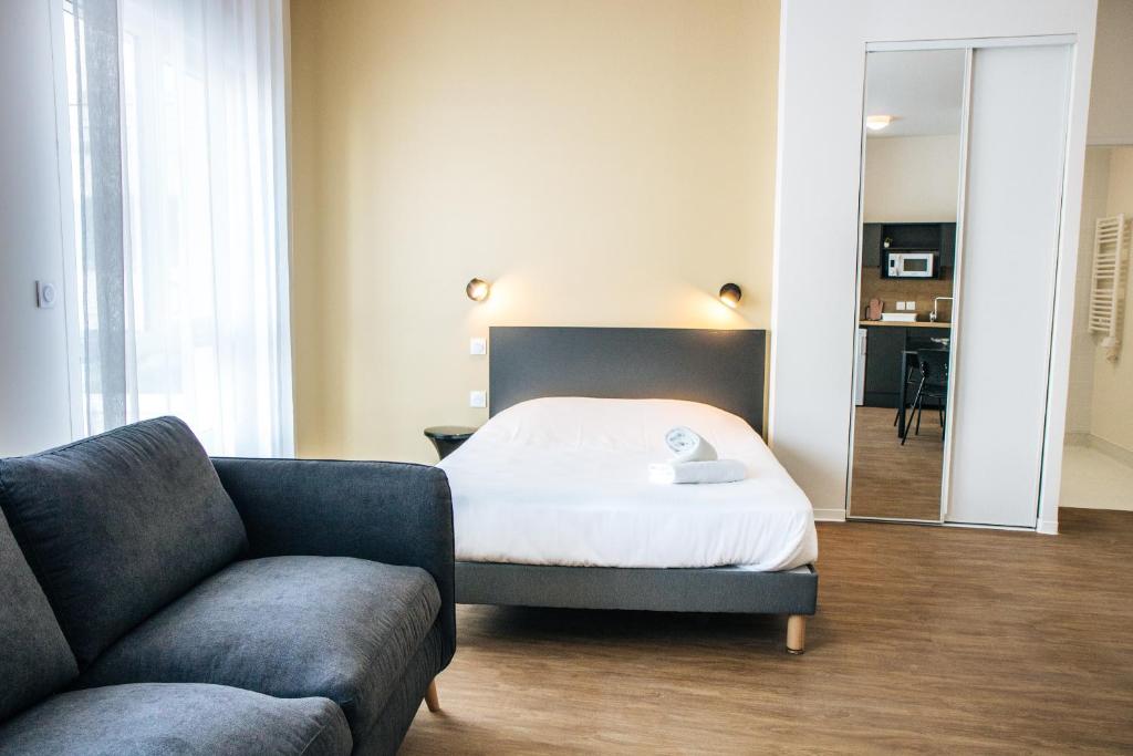 a bedroom with a bed and a couch and a mirror at Twenty Business Flats Béziers in Béziers