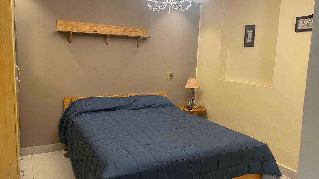 a bedroom with a bed with a blue blanket at Bernardo’s Departamento céntrico para 2 o hasta 3 personas in Sucre