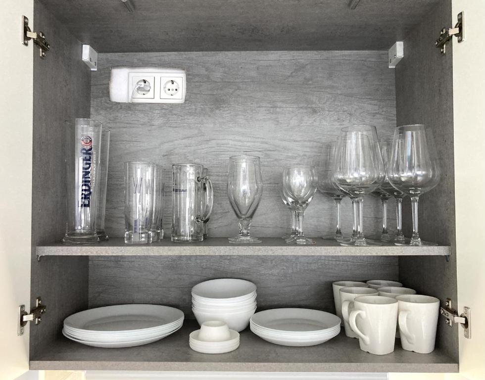 a shelf with wine glasses and plates and bowls at Living at Saarpartments with 2 Bedrooms, Netflix- Business & Holiday Apartments for Long- and Short term Stay, 3 min to Train-Station and Europa Galerie in Saarbrücken