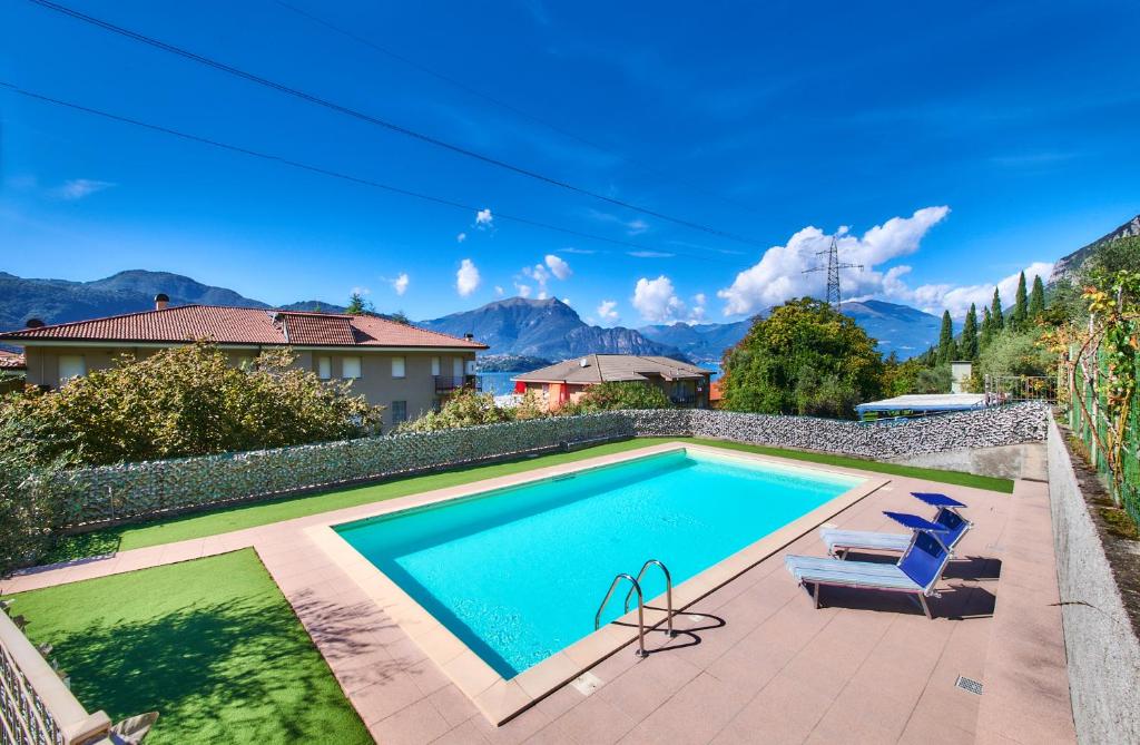 a swimming pool with two chairs and a house at Welcome Home Apartment in Lierna