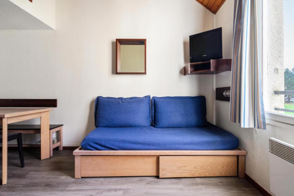 Cette chambre comprend un lit bleu et un bureau. dans l'établissement Résidence Port du Crouesty - maeva Home - Appartement duplex 3 pièces 7 personnes Confort MAE-4807, à Arzon