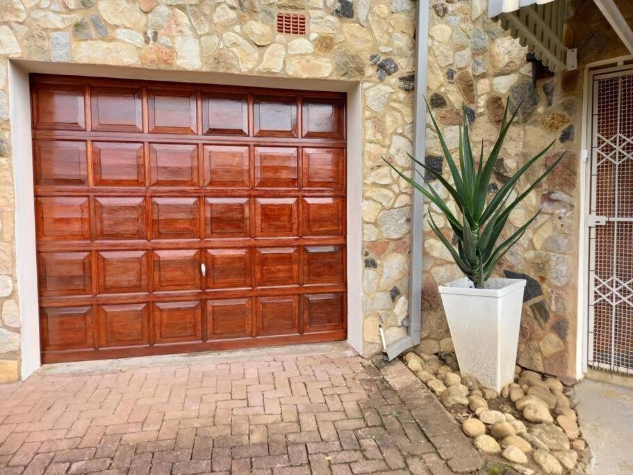 a wooden garage door with a potted plant in front of a house at Het Kadootje - Southbroom's little gift - 6 sleeper 3 bedroom apartment in Southbroom