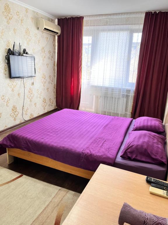 a purple bed in a room with a window at Однокомнатная квартира в Жилгородке рядом с ДостарМед in Atyraū