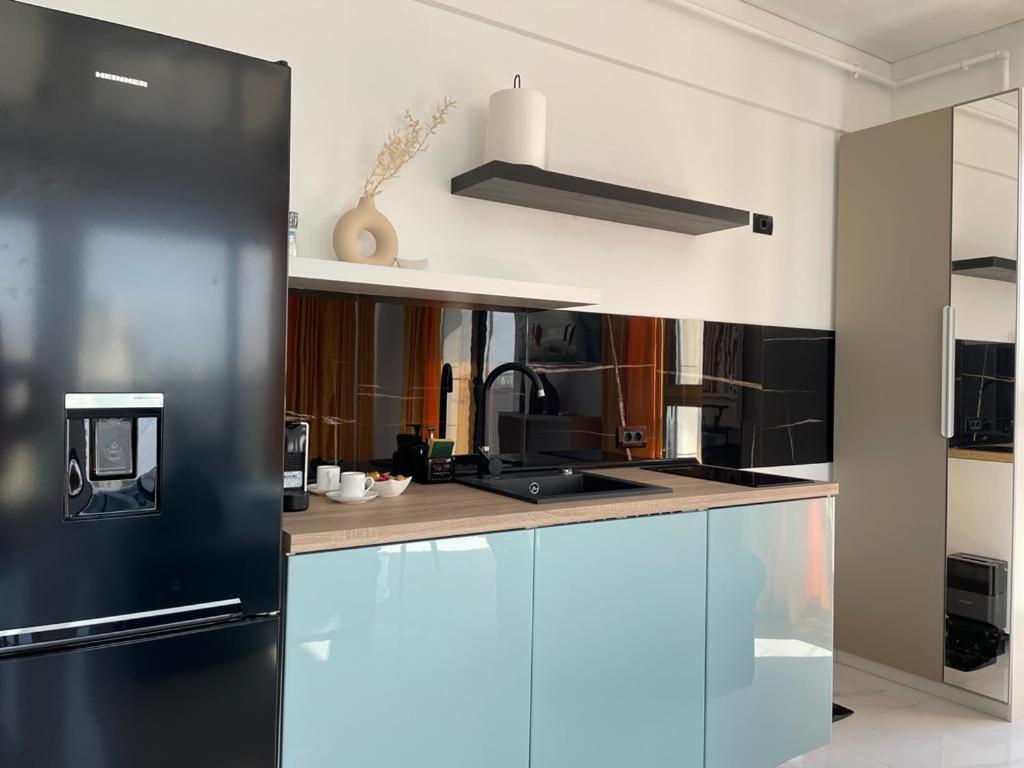 a kitchen with a black refrigerator in a room at Shiba studio Mamaia in Mamaia
