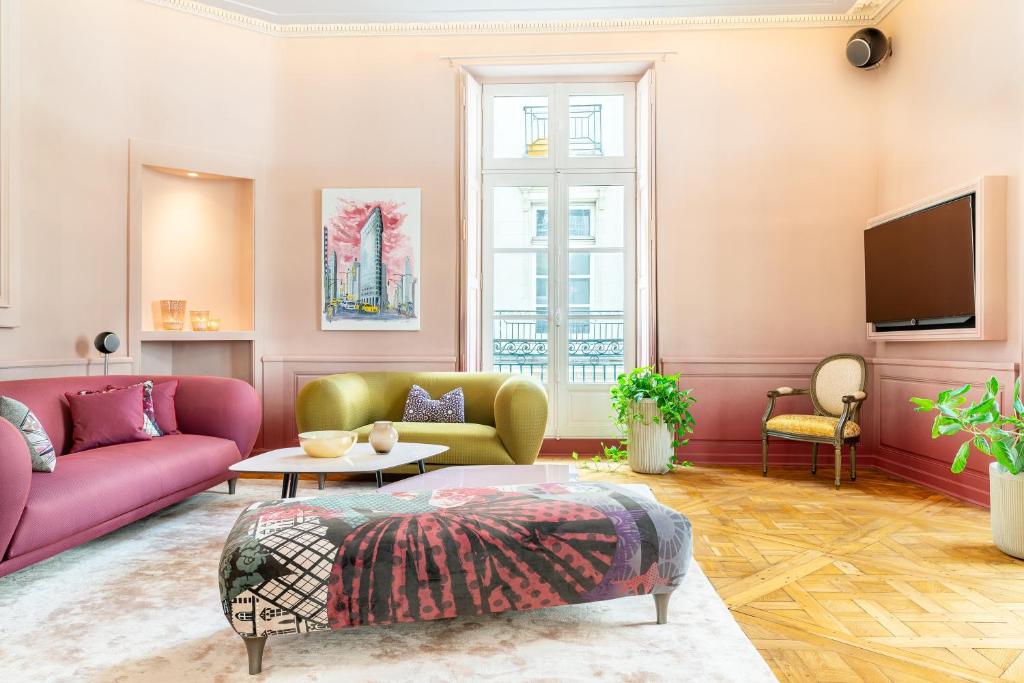 ein Wohnzimmer mit rosa Möbeln und einem Fernseher in der Unterkunft Le Crébillon - Splendide appartement de 204m2 in Nantes