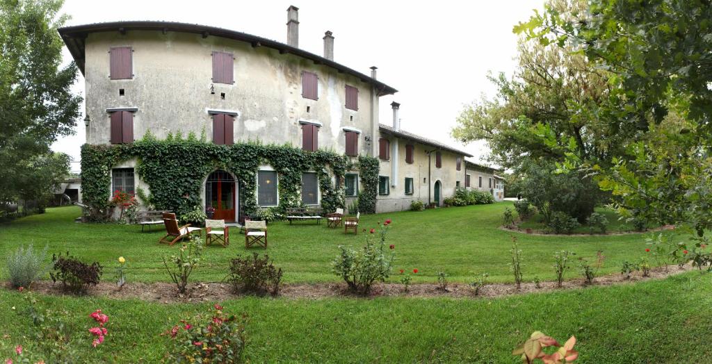 um grande edifício com um quintal com mesas e cadeiras em Casa Filaferro em Palazzolo dello Stella