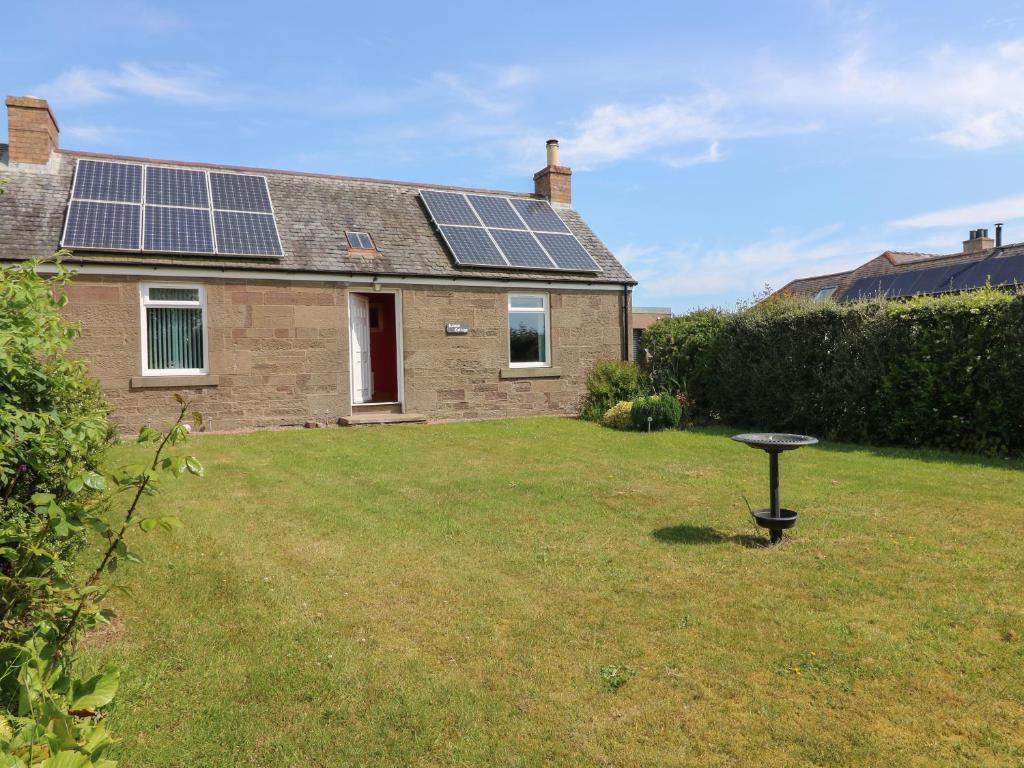 a house with solar panels on top of a yard at Rowan Cottage in Arbroath