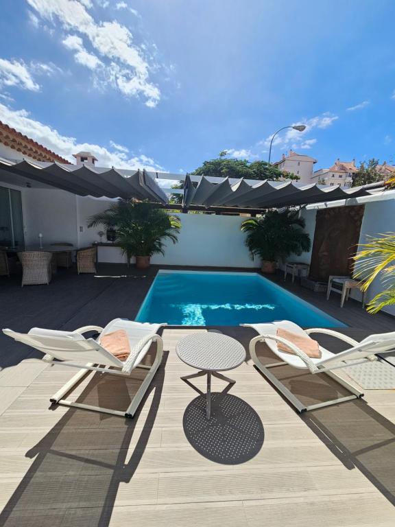 洛斯克里斯蒂亞諾斯的住宿－Nosotros Luxury Villa，一个带两把椅子的庭院和一个游泳池