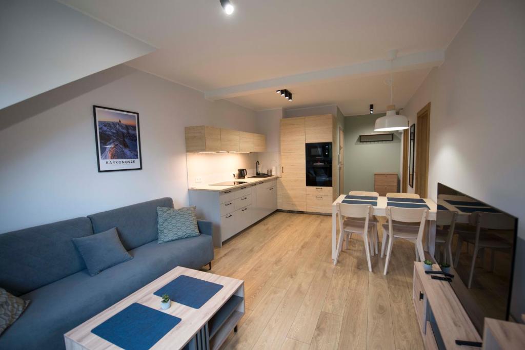 a living room with a blue couch and a kitchen at Apartament Pod Reglami in Szklarska Poręba