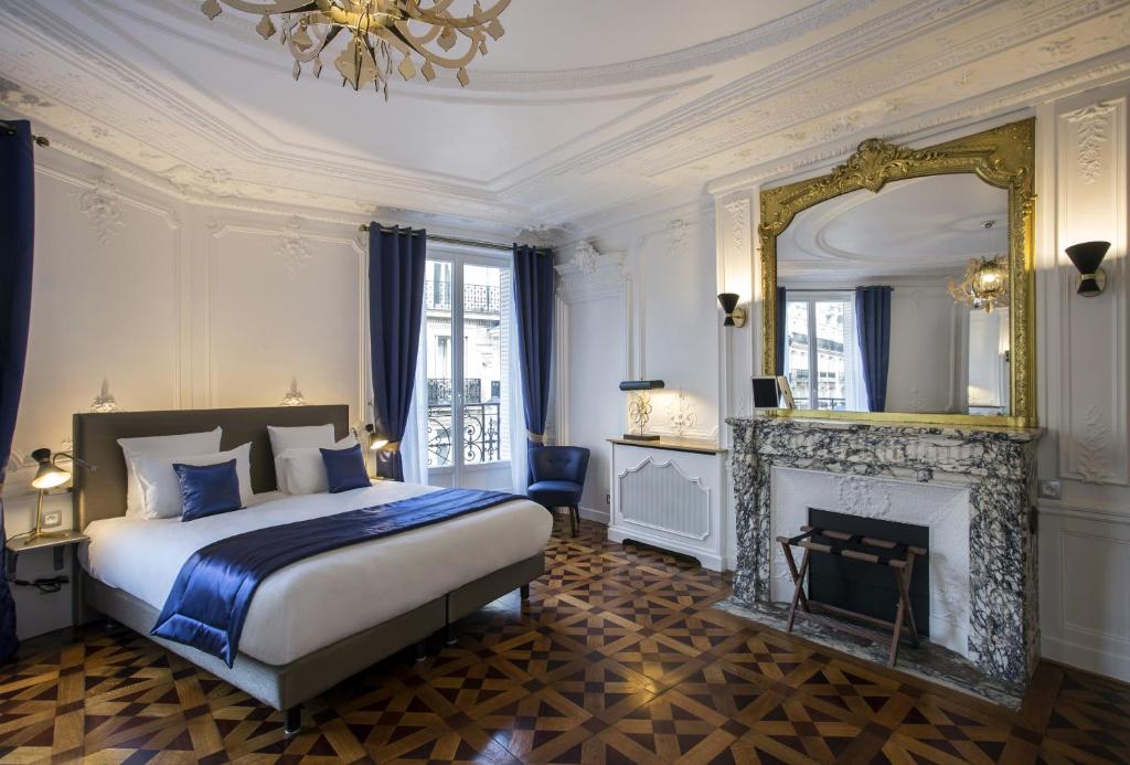 - une chambre avec un lit, une cheminée et un miroir dans l'établissement Vestay George V, à Paris