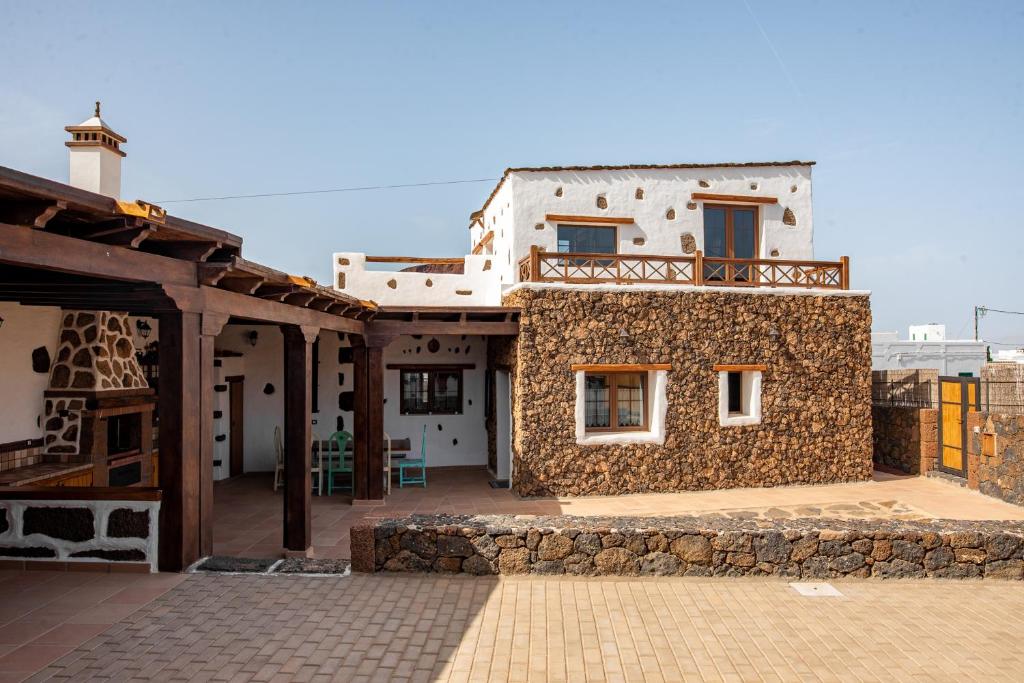 une maison avec un mur en pierre et un balcon dans l'établissement Casa Tilama, à Tinajo