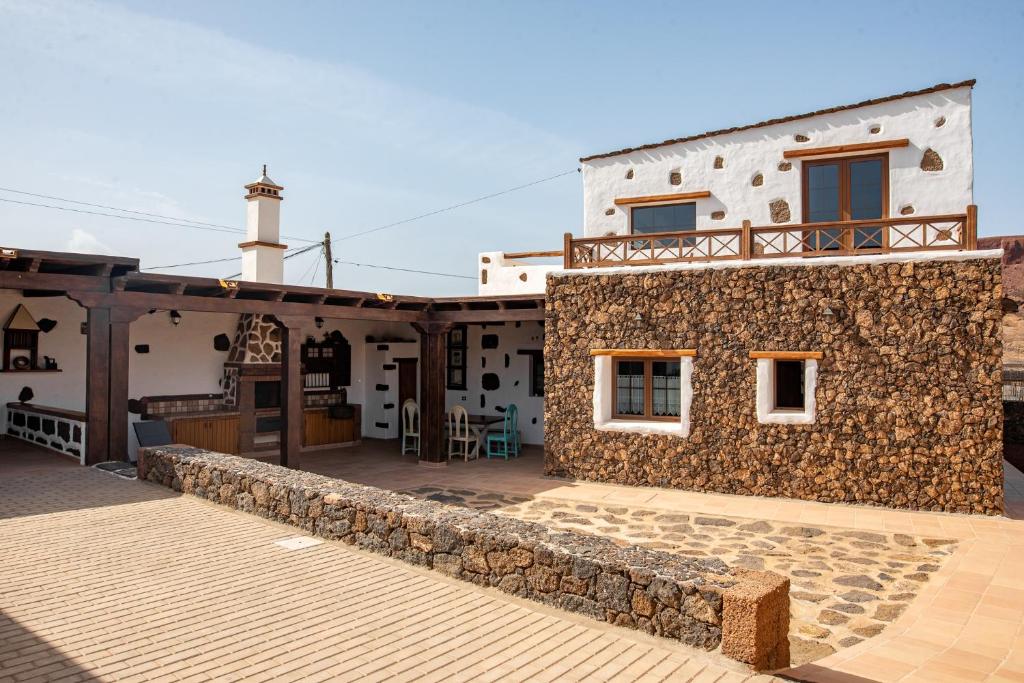 a house with a stone wall and a patio at Casa Tilama in Tinajo