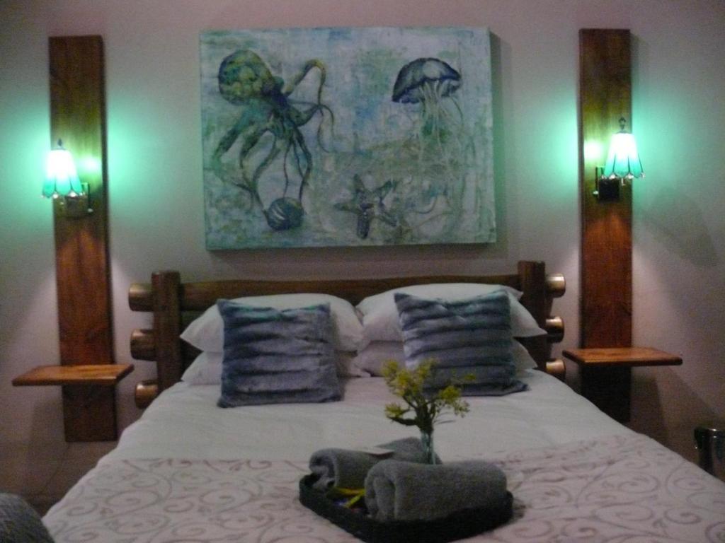 een slaapkamer met een bed met kussens en een schilderij bij THE ORCHID GUESTHOUSE 