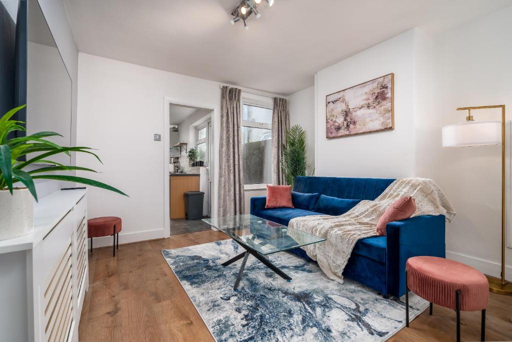 ein Wohnzimmer mit einem blauen Sofa und einem Glastisch in der Unterkunft Watford Casa - 2 bed and 2 bath home near Watford Junction Station in Watford