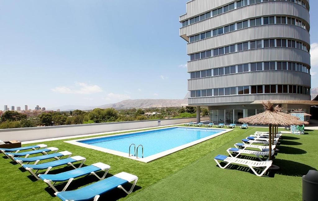 a swimming pool with lounge chairs and a building at La Estación in Benidorm