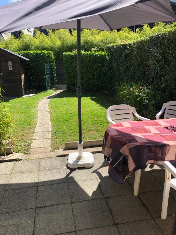 une table et des chaises avec un parasol sur une terrasse dans l'établissement Le cottage, à Villers-sur-Mer