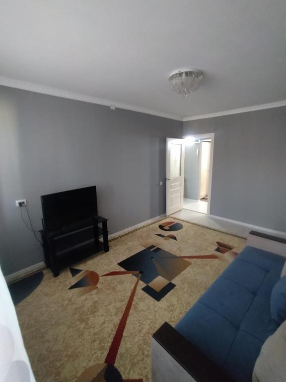 ein Wohnzimmer mit einem Sofa und einem TV in der Unterkunft 2-х комнатная квартира in Qysylorda