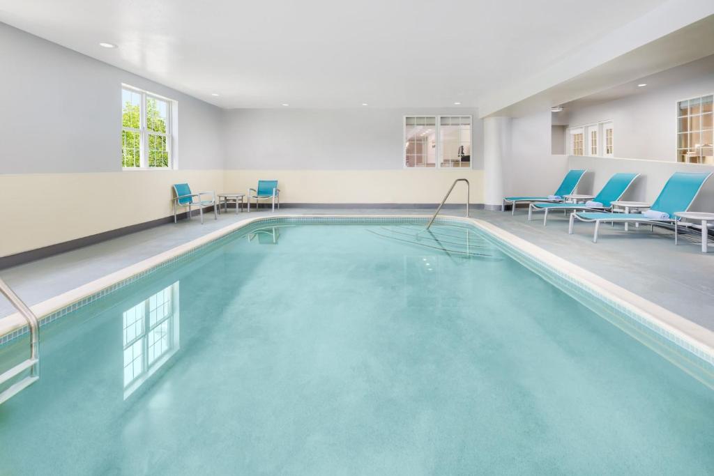 a swimming pool with blue chairs in a building at TownePlace Suites Manchester-Boston Regional Airport in Manchester