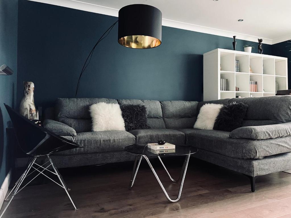 een woonkamer met een grijze bank en een tafel bij Luxury mid century Apartment in Londen