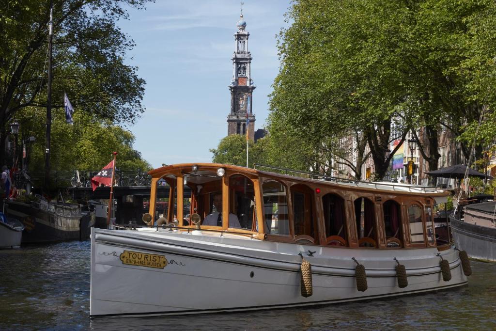 a boat on a river with a clock tower in the background at Pulitzer Amsterdam in Amsterdam