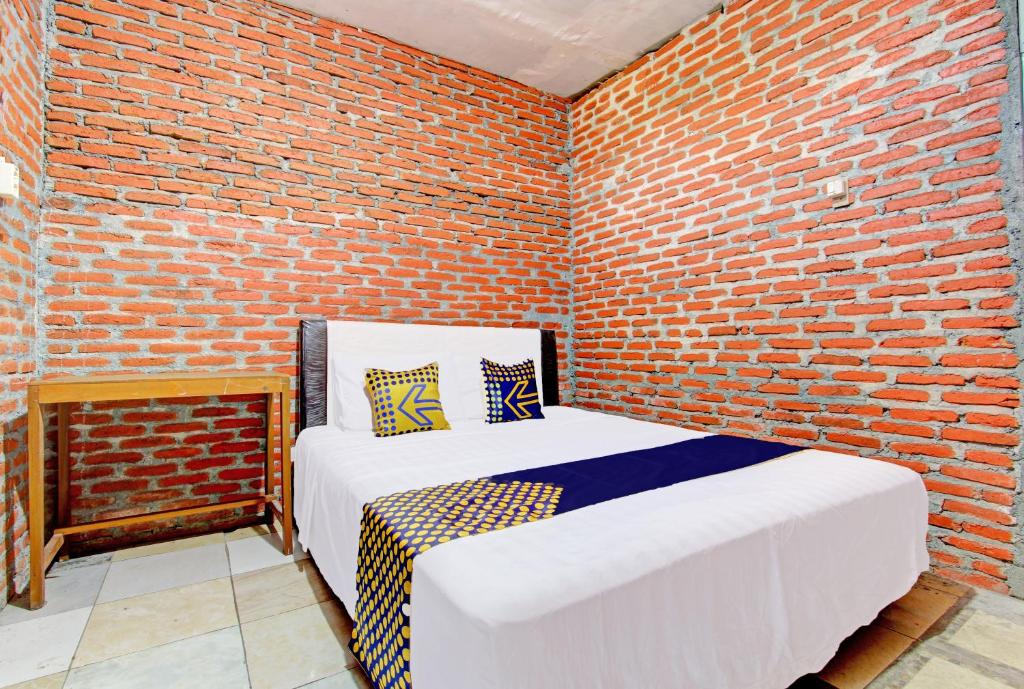 a bedroom with two beds in a brick wall at OYO Life 93010 Omah Bareng Syariah Sambisari in Kalasan