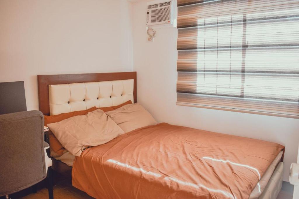 ein Schlafzimmer mit einem Bett mit einer orangefarbenen Bettdecke und einem Fenster in der Unterkunft AiPad Condo Rentals in Davao City
